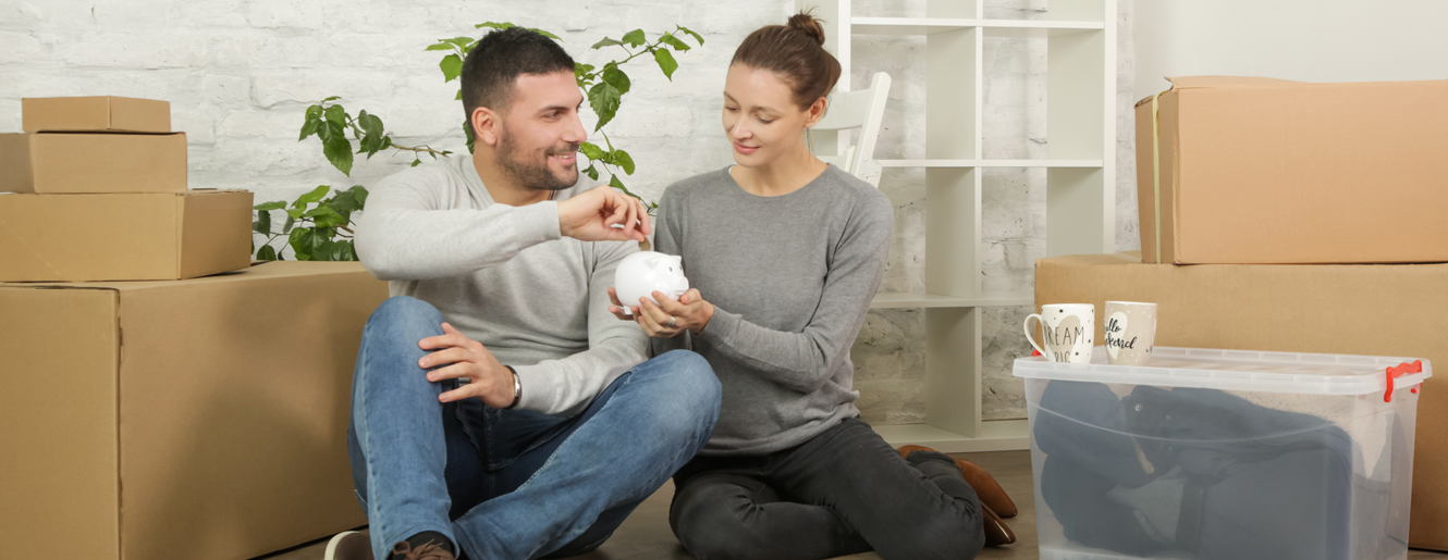 Young couple putting money in piggy bank.